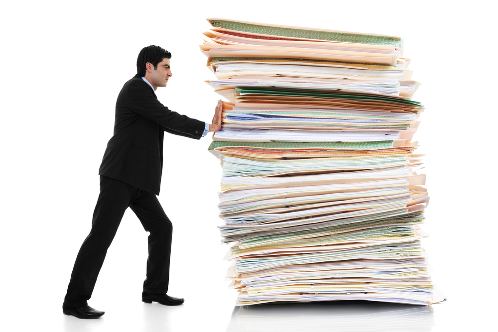 businessman pushing a giant stack of documents isolated on white background