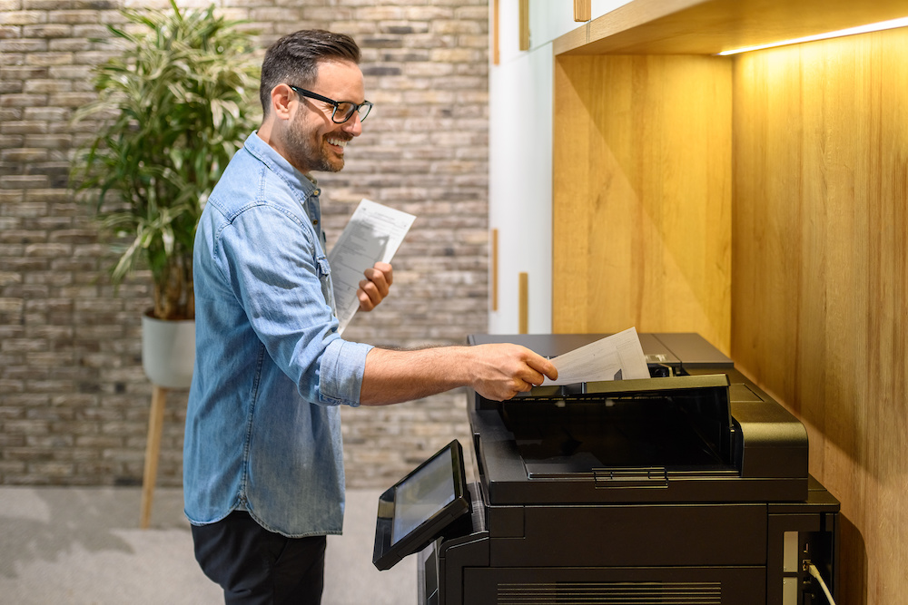 A man using the printer. He is trying to cut down on print costs.